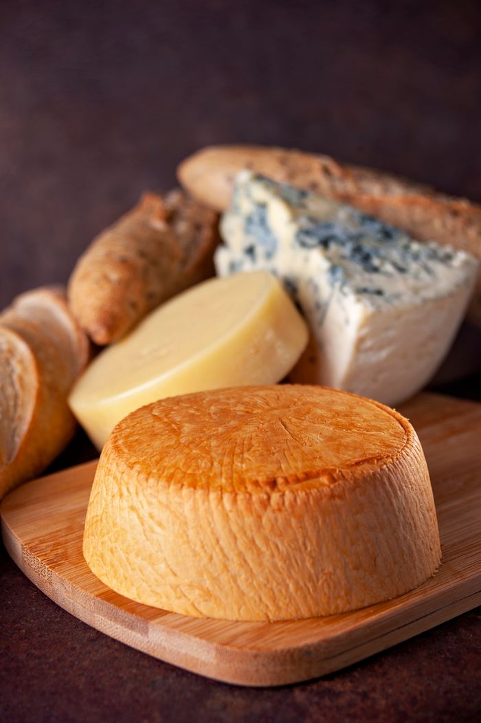 A variety of artisanal cheeses and bread displayed on a wooden board, ideal for gourmet presentations.