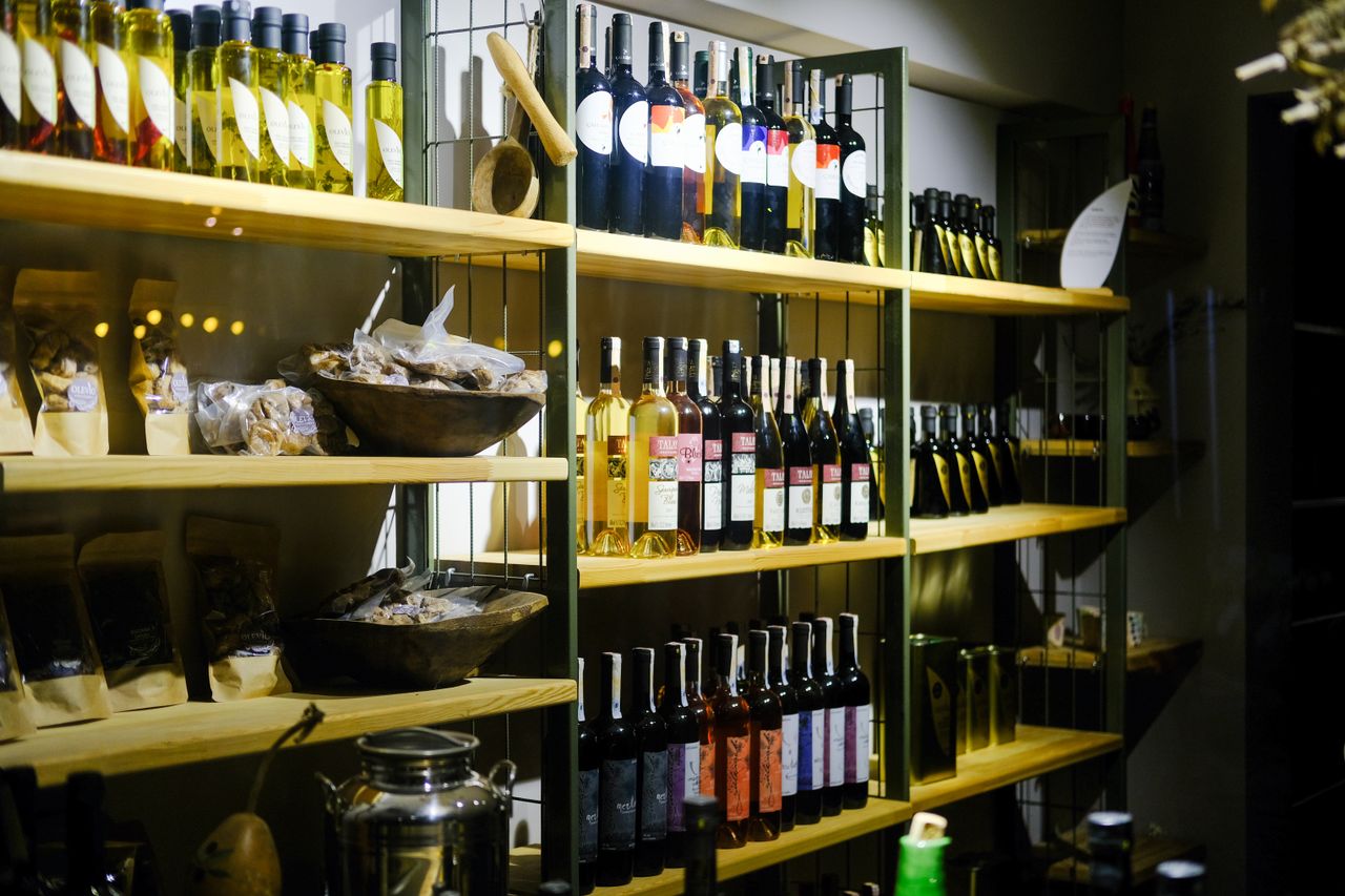 A variety of wine bottles displayed on wooden shelves in a Bozcaada retail store.